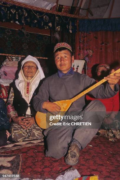 KAZAKH MUSICIAN PLAYING DOMBRA, THE LOCAL STRINGED INSTRUMENT, INSIDE YURT, KHOVD PROVINCE, MONGOLIA.