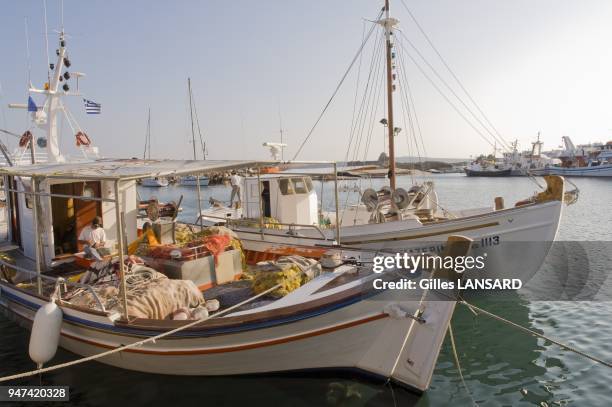 Deux marins pecheurs reparent les filets sur leur chalutier de bois dans le port de Naoussa, two fishermen repairing nets on their wooden boat in the...