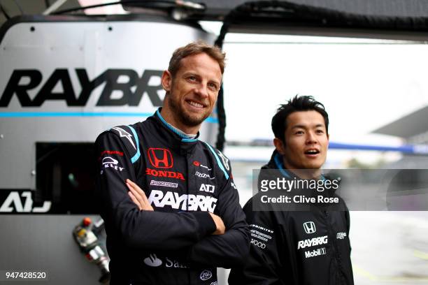 Jenson Button of Great Britain and teammate Naoki Yamamoto of Team Kunimitsu Honda Raybrig NSX-GT look on together in the pits during the Autobacs...