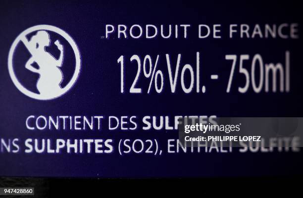 Picture taken on April 17 in Paris shows the label on a French wine bottle with an icon picturing a forbidden sign on a pregnant woman drinking. -...