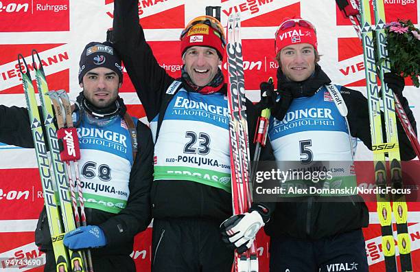 Winner Christoph Sumann of Austria poses on the podium together with Simon Fourcade of France who placed second and Alexander Os of Norway who placed...