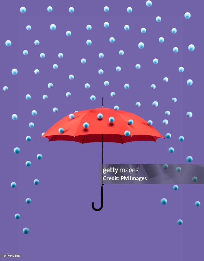 Symbolic rain drops falling on red umbrella