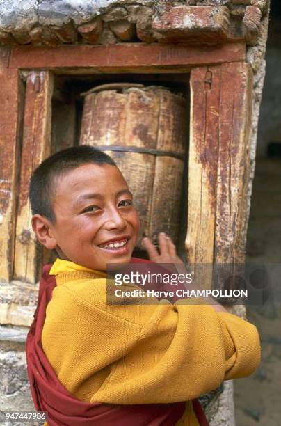 Lingshed, a novice monk turning the prayer wheel. Along with the small prayer wheels that all carry with them, in monasteries there are also wooden,...