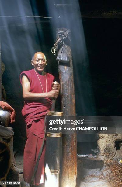 Monk. Making salt-butter tea in copper-bound wooden churn. Salt-butter tea is drank in large quantities by the entire population. It helps to fight...