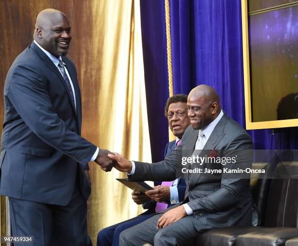 Los Angeles Lakers Ervin Magic Johnson applaudes as Shaquile O'Neal shakes hands with Hall of Famer Elgin Baylor during the unveiling ceremony for...