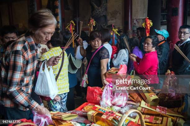 Visitors place offerings on a table as they queue to pray before a statue of Mazu at Xingang Fengtian Temple where it is being displayed for one day...