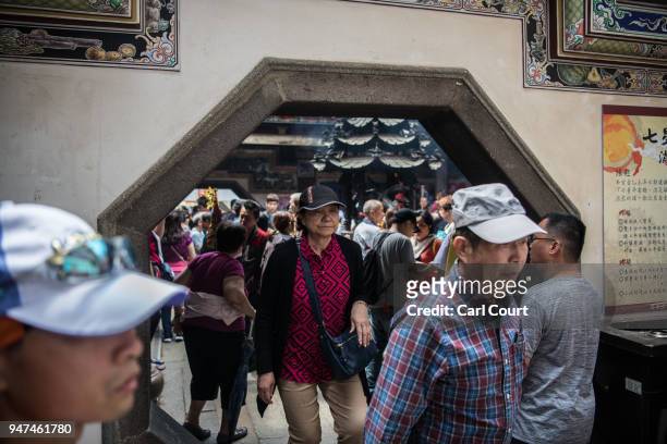 People walk a traditional archway as they visit Xingang Fengtian Temple on day five of the nine day Mazu pilgrimage on April 17, 2018 in Xingang,...