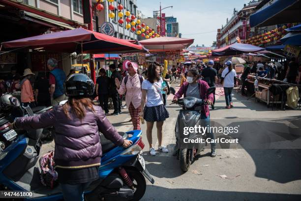 People pass along a street market while festivities take place to mark the attendance of a statue of Mazu at the nearby Xingang Fengtian Temple on...