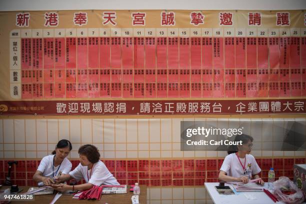Volunteers work under a banner announcing charitable donations to Xingang Fengtian Temple on day five of the nine day Mazu pilgrimage on April 17,...