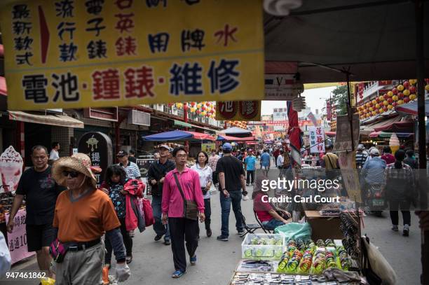 People pass along a street market while festivities take place to mark the attendance of a statue of Mazu at the nearby Xingang Fengtian Temple on...