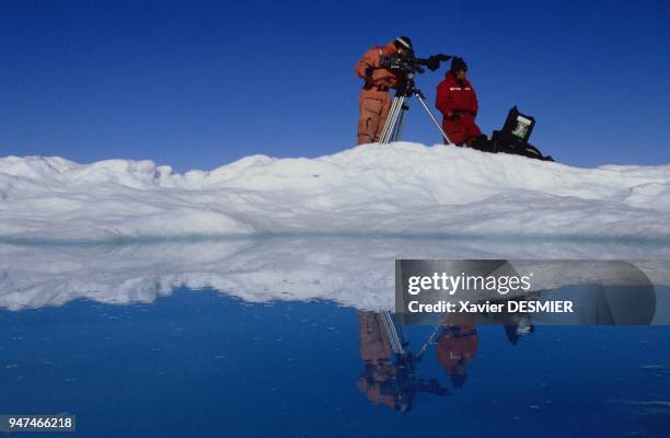 The cameraman, Thierry Machado, and his canadian assistant Stéphane Paillard watch and film a bowhead Whale when ice field melts in july between...