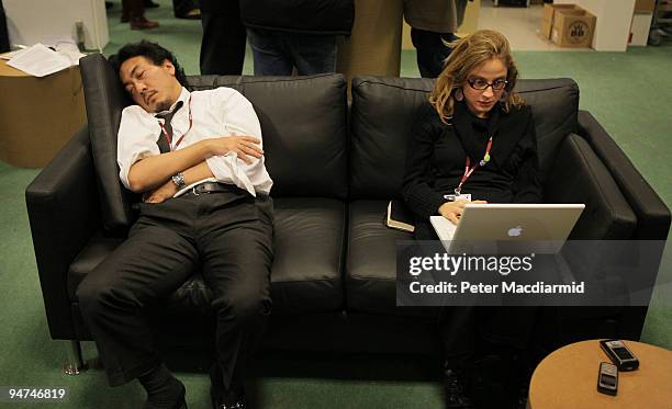 One journalist sleeps while another works in the main press room on the final day of the UN Climate Change Conference on December 18, 2009 in...