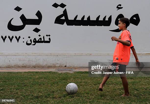 Local child strikes the ball as he plays football with others in the 2008/2009 season away shirt of FC Barcelona on December 18, 2009 in Abu Dhabi,...