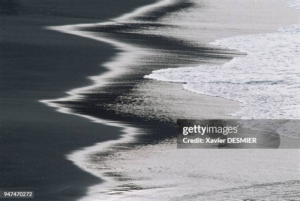 During the eastern storms, waves unfurl on the black-sand beach of the American bay. Pendant les tempêtes d'est, les vagues déferlent sur la plage de...