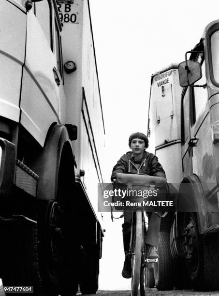 Dangers de la route, enfant à vélo passant entre deux camions.