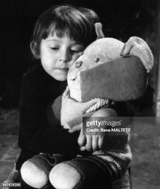 Enfant serrant son ours en peluche contre lui.