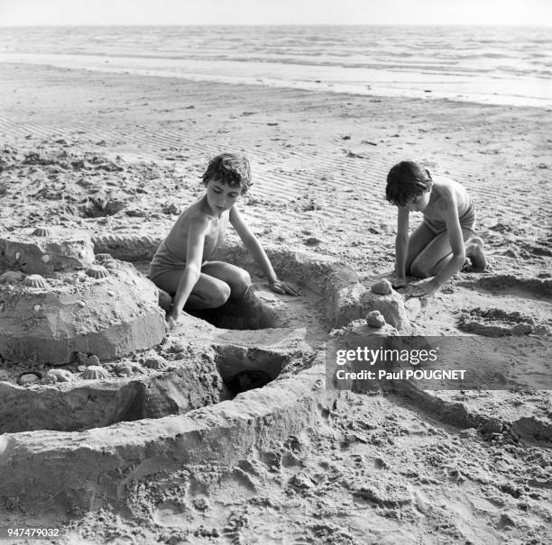 Enfant construisant un château de sable, sur un plage.