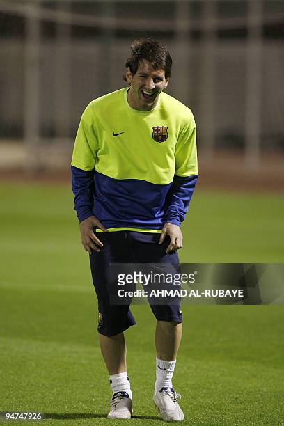Barcelona's Argentine striker Lionel Messi laughs as he attends a training session in the Gulf emirate of Abu Dhabi on December 18 on the eve of...