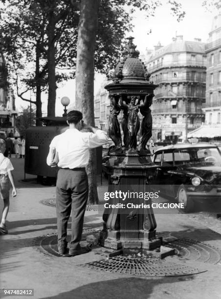 Un homme se sert à boire à une fontaine Wallace.