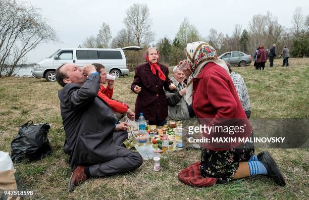People drink and eat as they picnic near a cemetery in the village of Orevichi, inside the exclusion zone around the Chernobyl nuclear reactor, some...
