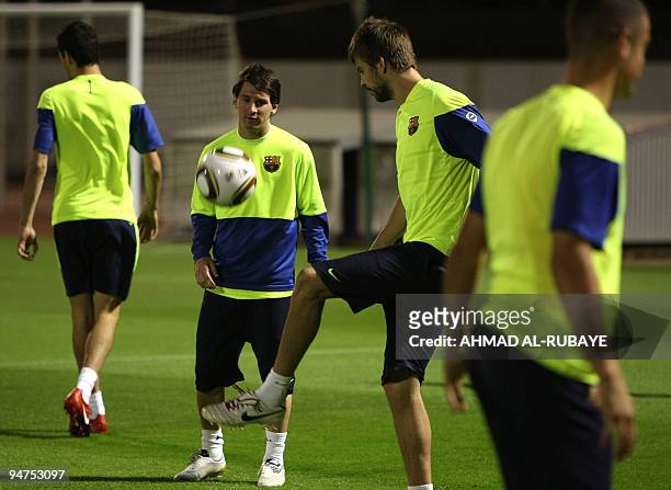 Barcelona's Argentine striker Lionel Messi practices with teammate Gerard Pique during a training session in the Gulf emirate of Abu Dhabi on...