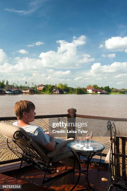 Man looking over the Chao Phraya during a cruise on the Anantara Dream, a 100-year old refurbished teak river boat.