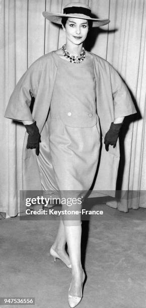 Costume de lin gris ardoise er beige chapeau de paille garni en noir, collection printemps. Londres le 28 novembre 1957.