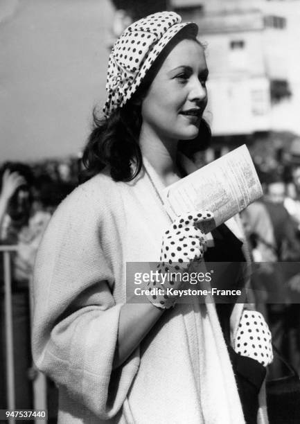 Jeune femme élégante, casquette et gants à pois, aperçue au pesage de Chantilly lors du Prix de Diane, Paris le 03 juin 1951.