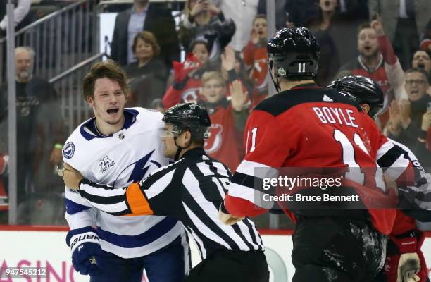 Linesman escourts Mikhail Sergachev of the Tampa Bay Lightning off the ice following a third period fight against Brian Boyle of the New Jersey...