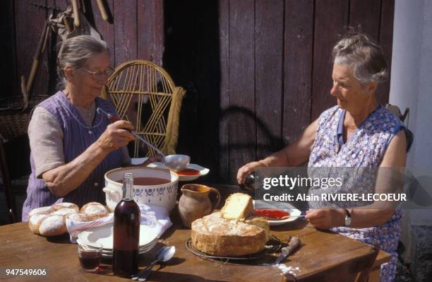 Femmes âgées ?faisant chabrot?, en ajoutant du vin rouge dans la soupe, en Bourgogne, France.