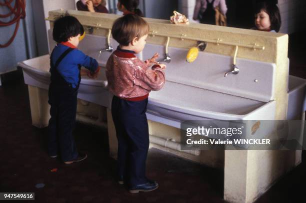 Enfants se lavant les mains dans les toilettes d'une école maternelle en France.