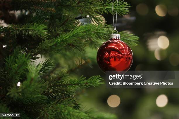 a christmas bauble hangs from a tree - boule de noël photos et images de collection