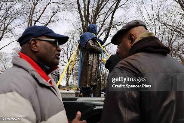 Men discuss the covered statue of J. Marion Sims, a surgeon celebrated by many as the father of modern gynecology, before it is driven away in a...