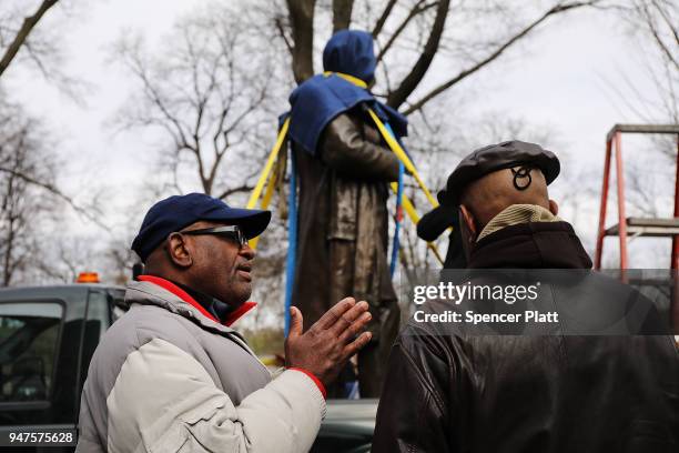 Men discuss the covered statue of J. Marion Sims, a surgeon celebrated by many as the father of modern gynecology, before it is driven away in a...