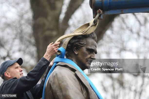 Parks Department worker fastens a statue of J. Marion Sims, a surgeon celebrated by many as the father of modern gynecology, before it is driven away...