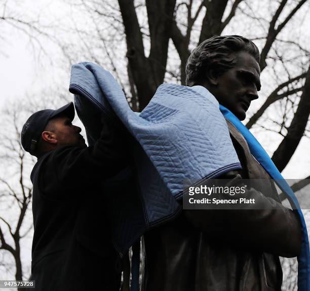 Parks Department worker fastens a statue of J. Marion Sims, a surgeon celebrated by many as the father of modern gynecology, before it is driven away...