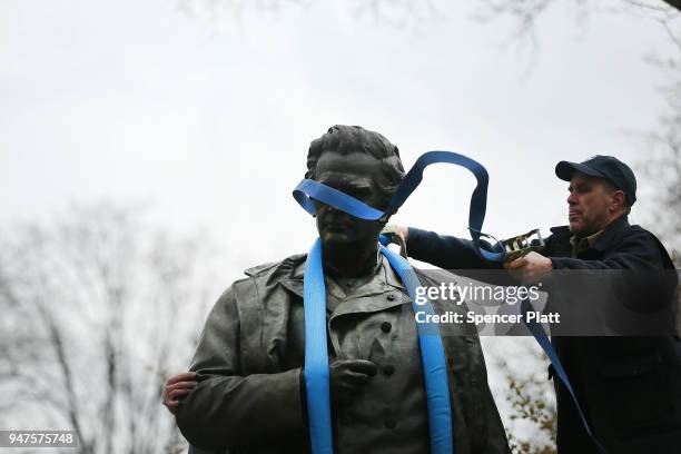 Parks Department worker places a harness over a statue of J. Marion Sims, a surgeon celebrated by many as the father of modern gynecology, before it...