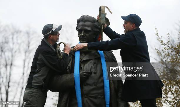 Parks Department workers place a harness over a statue of J. Marion Sims, a surgeon celebrated by many as the father of modern gynecology, before it...