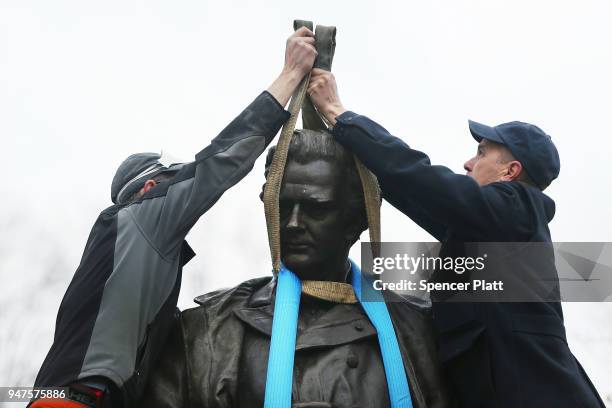 Parks Department workers place a harness over a statue of J. Marion Sims, a surgeon celebrated by many as the father of modern gynecology, before it...