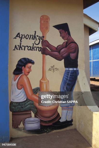 Décoration à l'extérieur d'un café, un homme et une femme autour d'un pilon, au Ghana.