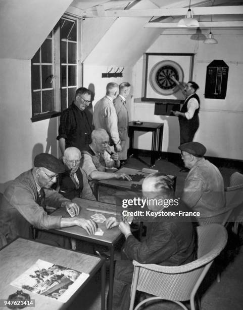 De vieux hommes jouent aux cartes ou aux fléchettes pendant leur pause déjeuner avant de retourner à l'atelier, dans un club de vétérans, au...