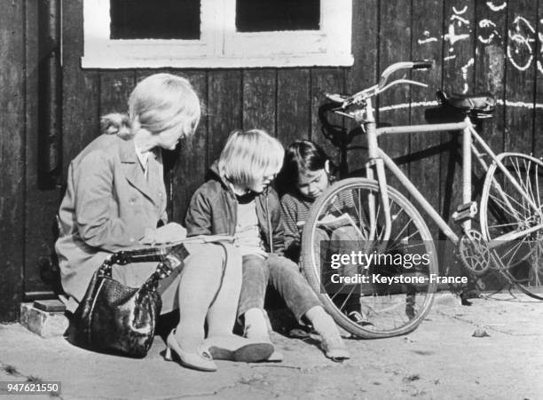 Une femme et deux enfants assis par terre près d'un vélo à l'école publique et libre de Summerhill, au Royaume-Uni.