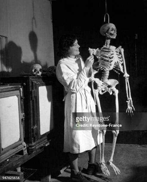 Une technicienne accroche le bras d'un squelette en plastique au reste du corps, après avoir fait cuire les os de plastique dans les fours derrière...