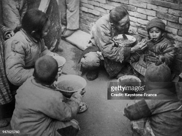 Un Chinois donnant à manger à quelques petits Chinois affamés, en Chine en 1935.