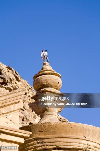 Young bedouins Ahmed Salem Albidul and Atef Salem Albidul climbing on top of the urne. The Deir, also called Monastery,has been carved in the rock on...