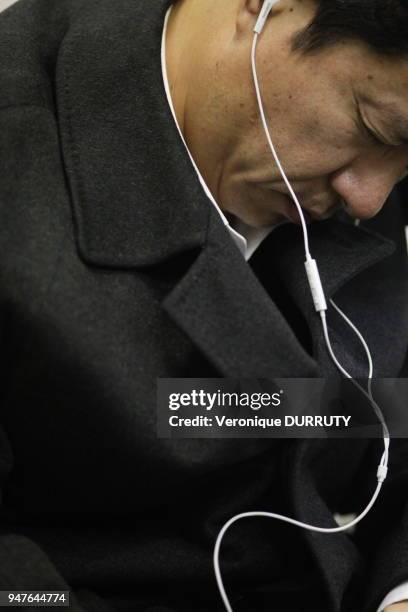 Homme endormi, ecoutant de la musique au casque dans le metro de Tokyo, Japon.