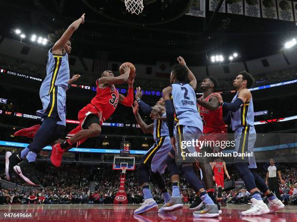 Kris Dunn of the Chicago Bulls drives between Deyonta Davis and Kobi Simmons of the Memphis Grizzlies at the United Center on March 7, 2018 in...