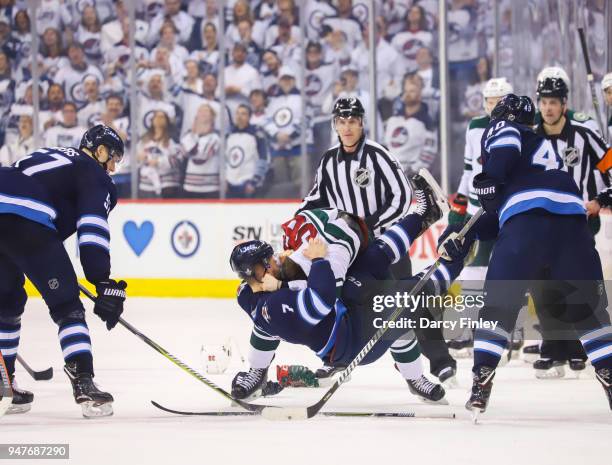 Nick Seeler of the Minnesota Wild takes down Ben Chiarot of the Winnipeg Jets during a third period fight in Game Two of the Western Conference First...