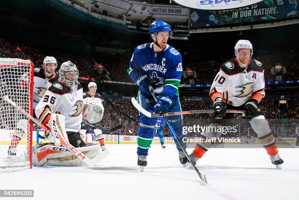 John Gibson of the Anaheim Ducks looks on as Corey Perry of the Anaheim Ducks checks Henrik Sedin of the Vancouver Canucks during their NHL game at...