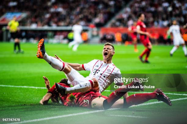 Joshua Kimmich is attacked by Panagiotis Retsos of Leverkusen during the DFB Cup semi final match between Bayer 04 Leverkusen and Bayern Muenchen at...